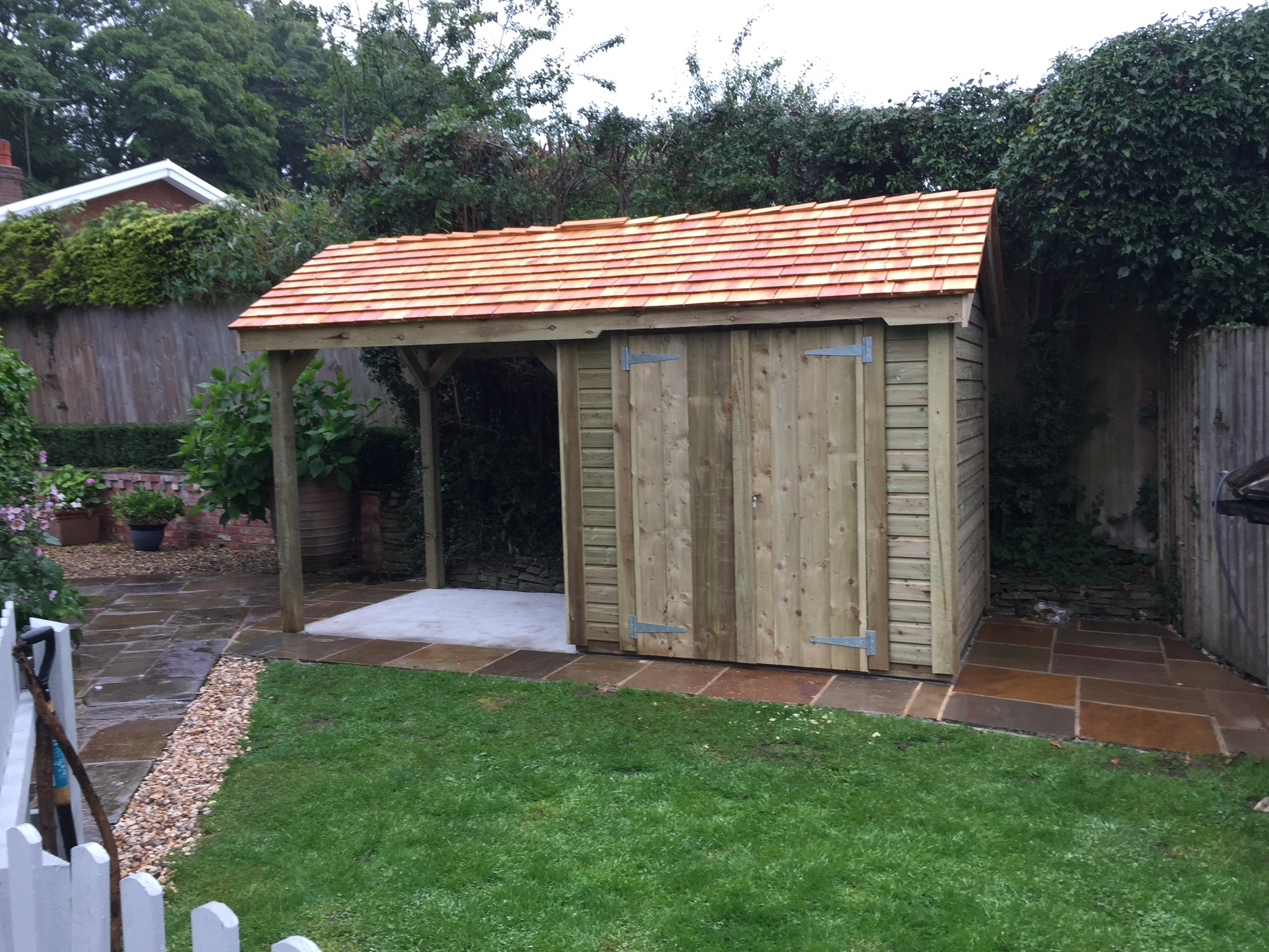 Timber structure with cedar shingle roof and storage for log storage and large storage cupboard section