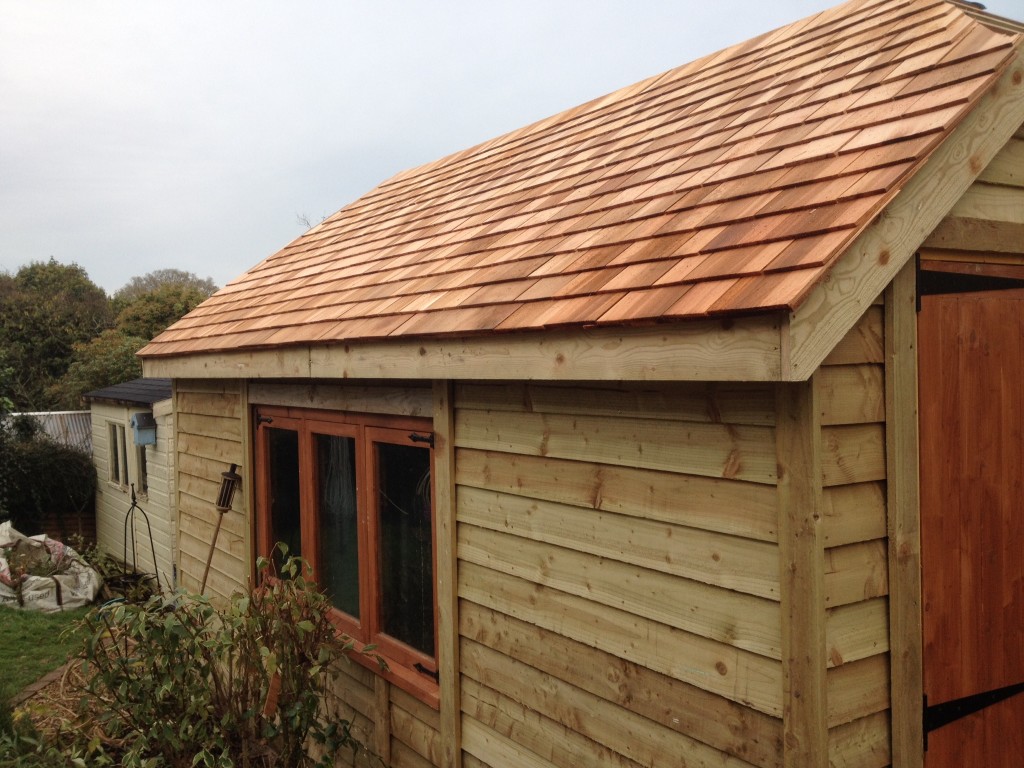 Timber garage with a cedar shingle roof and double doors