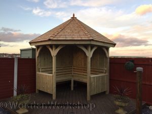 timber corner arbour with cedar shingle roof and internal seating 