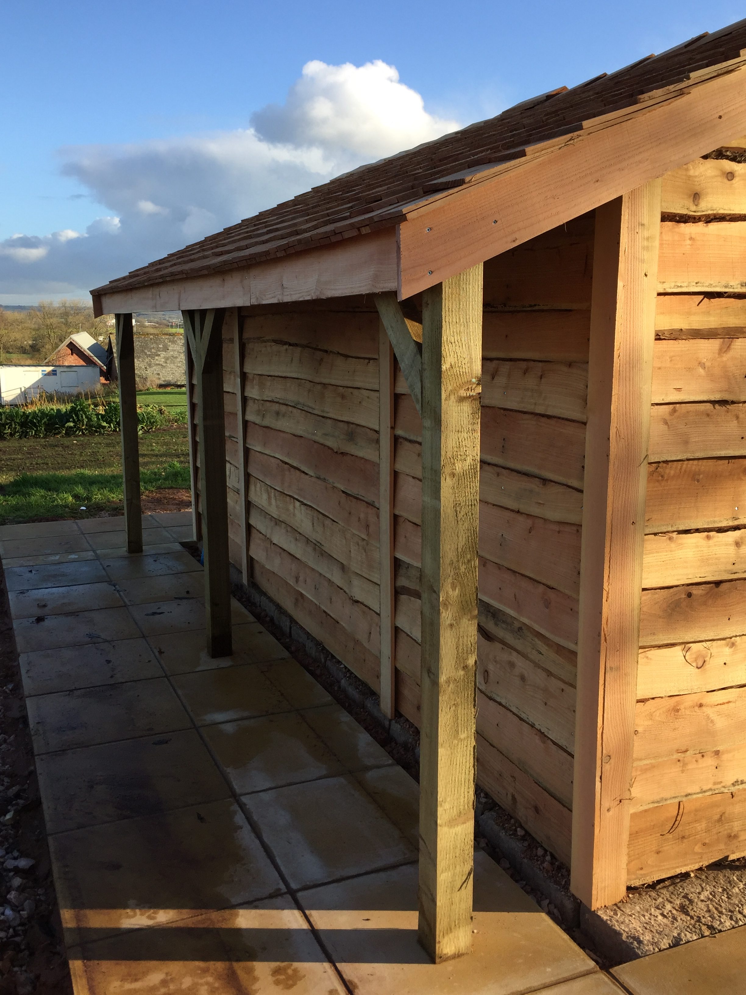 bespoke cedar shingle potting shed with a covered lean too area on the rear of the potting shed