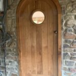Curved internal oak door with porthole window and brass ironmongery