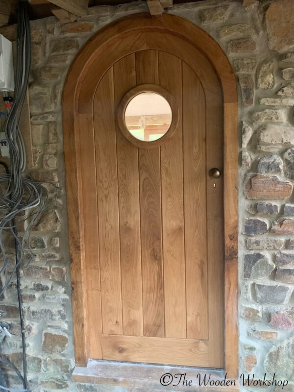 Curved internal oak door with porthole window and brass ironmongery